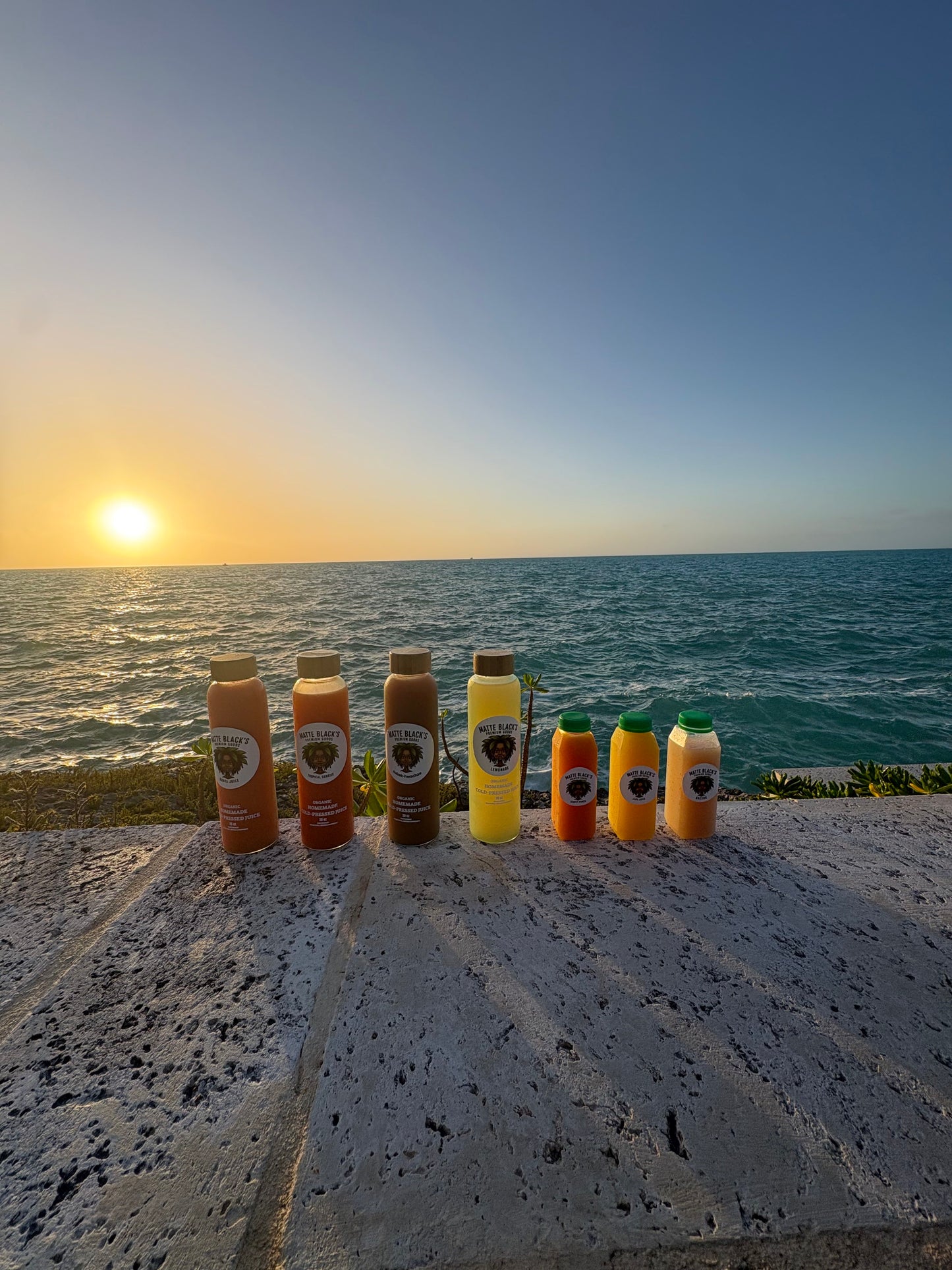 Sunset over a beach with bottles lined up on a ledge.