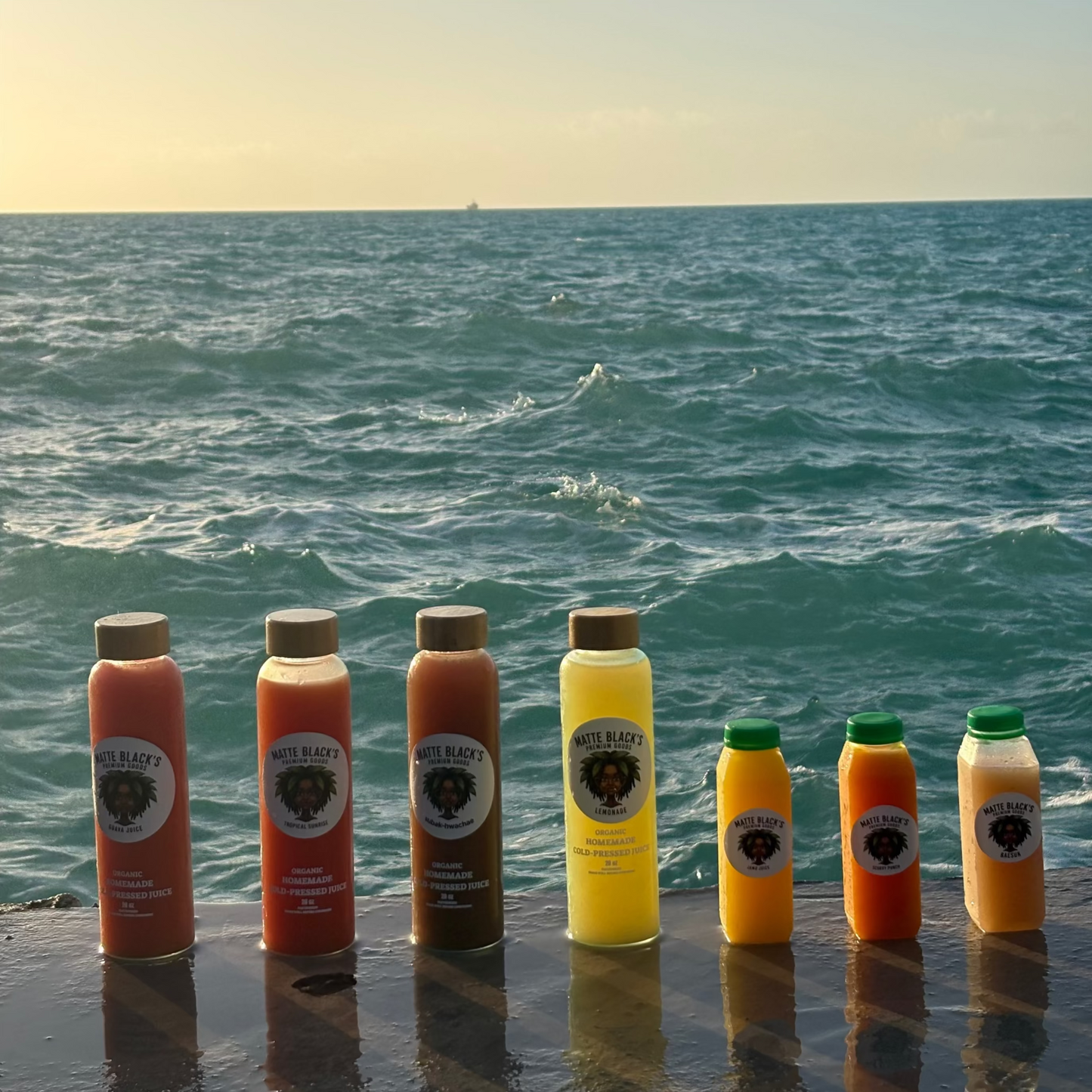 Row of juice bottles with visible labels against a backdrop of ocean waves.