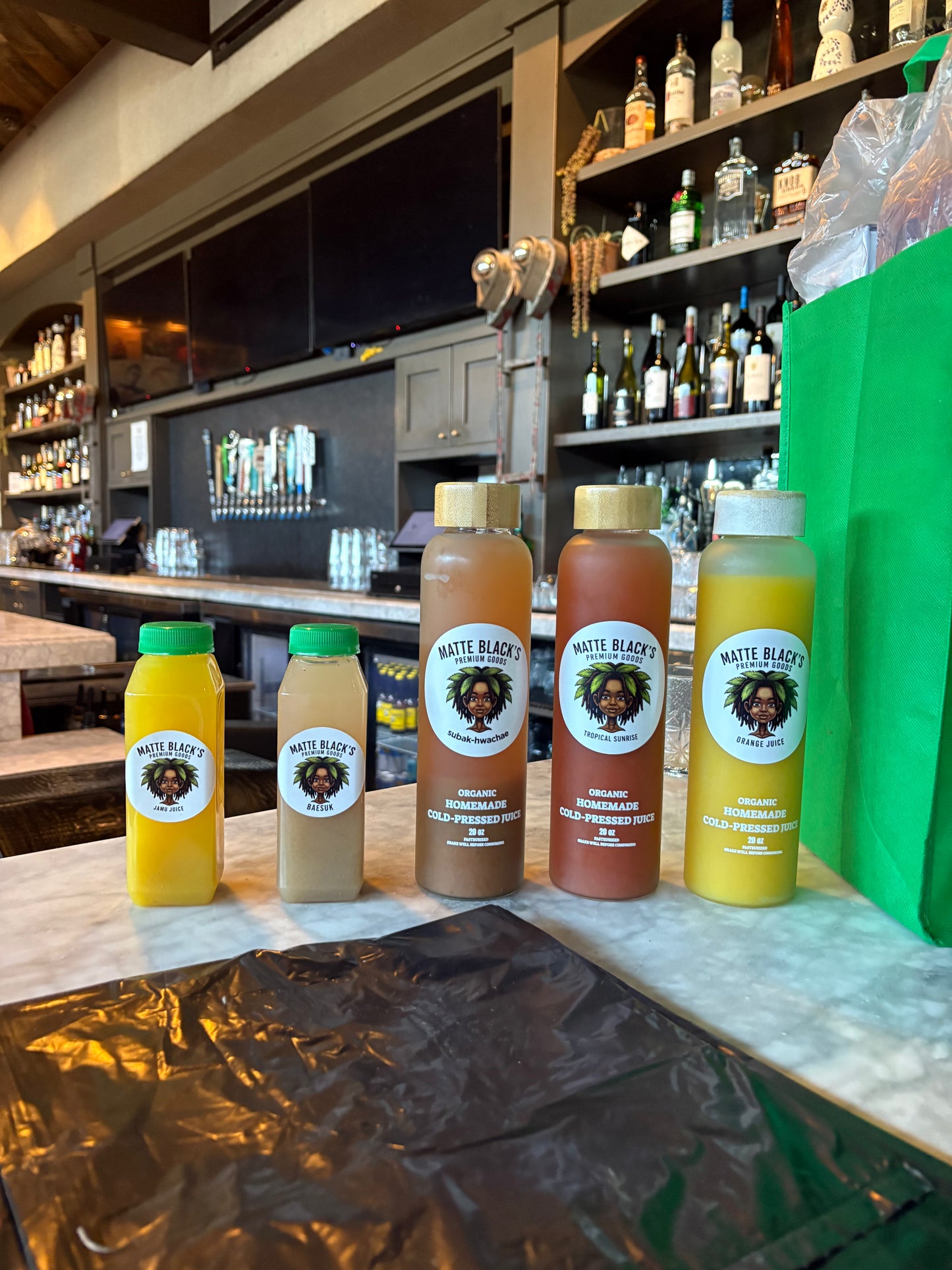 Five bottles of Matte Black's juice on a bar counter with a bar in the background.